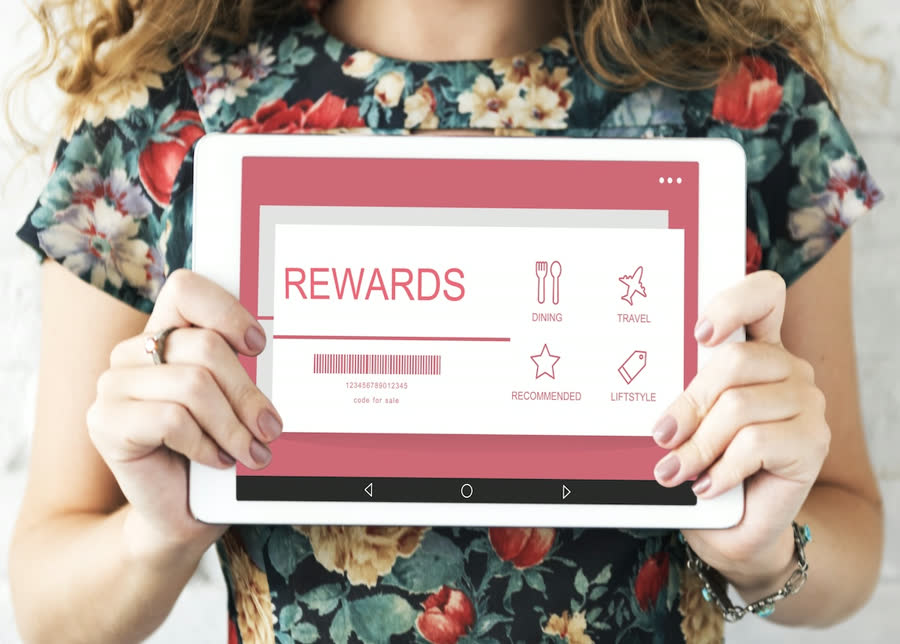 Woman holding a tablet displaying a rewards program screen