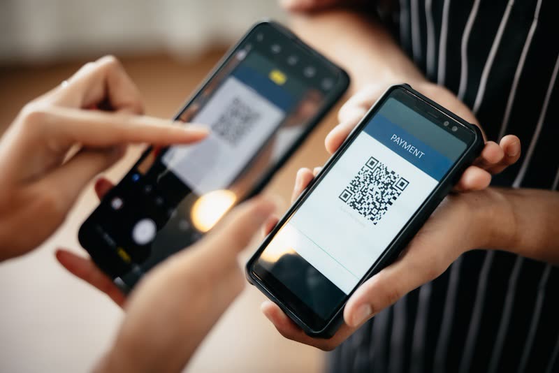 Two people completing a QR code payment on smartphones