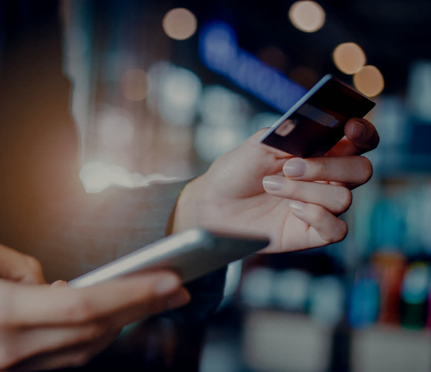 Person holding a payment card and a phone at night